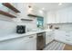 White kitchen has stainless appliances, farmhouse sink, and floating shelves with a view through the window at 16 Leeward Dr, Placida, FL 33946