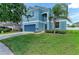 Charming two-story home with a blue exterior, well-manicured lawn, and mature palm tree at 1721 Palm Warbler Ln, Ruskin, FL 33570