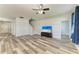 Living room featuring gray wood floors, a ceiling fan, and a large TV at 1721 Palm Warbler Ln, Ruskin, FL 33570
