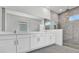 Modern bathroom with double vanity, large mirror, tiled shower, and stone tile flooring at 17723 Palmiste Dr, Bradenton, FL 34202