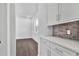 Hallway featuring hardwood floors, white cabinets, and a light-colored backsplash at 17723 Palmiste Dr, Bradenton, FL 34202