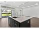 Bright kitchen showcasing an island with quartz countertops and dark cabinetry, opening to the backyard at 17723 Palmiste Dr, Bradenton, FL 34202
