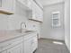 Well-lit laundry room featuring white cabinets, tile floors, sink, and a window at 17723 Palmiste Dr, Bradenton, FL 34202