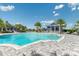 A large community pool surrounded by lounge chairs, blue umbrellas, palm trees and blue accented buildings at 17723 Palmiste Dr, Bradenton, FL 34202