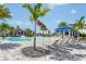 A resort style pool is surrounded by lounge chairs, blue umbrellas, palm trees and blue accented buildings at 17723 Palmiste Dr, Bradenton, FL 34202