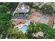 Aerial view showcasing the property's pool, tennis courts, parking area, and surrounding landscape at 1869 Springbush Ln, Clearwater, FL 33763