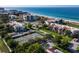Aerial view showcasing beachfront condos, a tennis court, and lush greenery in a coastal community at 2045 Gulf Of Mexico Dr # M1-514, Longboat Key, FL 34228