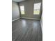 Bright bedroom with wood-look tile flooring and natural light from the two windows at 24779 Buckingham Way, Port Charlotte, FL 33980