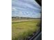 Backyard screened view featuring lush lawn, community view, and sunny skies at 24831 Buckingham Way, Port Charlotte, FL 33980