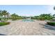 A luxurious community pool is surrounded by lounge chairs, palm trees, and lush landscaping at 2625 Star Apple Way, Sarasota, FL 34240