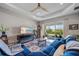 Cozy living room with a blue sofa, large window, ceiling fan and sliding glass doors to the backyard at 2625 Star Apple Way, Sarasota, FL 34240