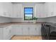Laundry room featuring bright white cabinets, sink, dark hardware, and modern washer and dryer at 3212 Signet Ct, Sarasota, FL 34240