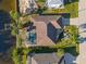 Aerial view of a charming single Gathering home featuring a screened in pool, lush tropical landscaping, and attached two car garage at 3415 Knox Ter, Port Charlotte, FL 33948