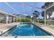 Inviting pool area with screened-in lanai, tropical landscaping, and privacy fence at 3415 Knox Ter, Port Charlotte, FL 33948
