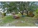 Lush backyard with mature trees, outdoor seating area, and fun playground set at 3810 Hidden River Rd, Sarasota, FL 34240