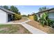 Well-maintained home exterior with lush landscaping, a paved walkway, and a view of the garage with modern design elements at 3810 Hidden River Rd, Sarasota, FL 34240
