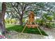 Backyard playground set with a slide, swings and artificial turf under a large tree at 3810 Hidden River Rd, Sarasota, FL 34240