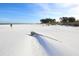 Picturesque white sand beach with a person walking along the shore and driftwood in the foreground at 407 63Rd St, Holmes Beach, FL 34217