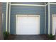 Attached one car garage with white door and blue siding at 5681 Bidwell Pkwy # 104, Sarasota, FL 34233