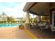Inviting pool area with seating on the veranda, tables, chairs, and views of other community buildings at 5681 Bidwell Pkwy # 104, Sarasota, FL 34233