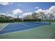 A well-maintained tennis court with a blue and green surface is surrounded by lush greenery at 613 E 49Th E St, Bradenton, FL 34208