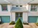 Facade of townhome featuring a light tile roof, twin turquoise doors, and a well-manicured landscape at 6572 Fairway Gardens Dr # 6572, Bradenton, FL 34203