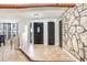Inviting foyer featuring tile floors, stone accent wall, and a rustic beam, offering a warm welcome to this unique home at 7321 Caladesia Dr, Sarasota, FL 34243
