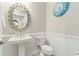 Elegant powder room featuring a pedestal sink, decorative mirror, and wainscoting at 7327 Summerland Cv, Bradenton, FL 34202