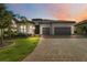 Beautiful exterior view of a home with a well-manicured lawn and a three-car garage with a tile roof at 7327 Summerland Cv, Bradenton, FL 34202
