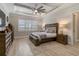 This main bedroom features a tray ceiling, ceiling fan, wood look tile flooring and a king bed at 7327 Summerland Cv, Bradenton, FL 34202