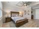 This main bedroom features a tray ceiling, ceiling fan, wood look tile flooring and a king bed at 7327 Summerland Cv, Bradenton, FL 34202