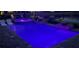 Backyard pool with hot tub and two small waterfalls, illuminated by colorful lights at night at 7327 Summerland Cv, Bradenton, FL 34202