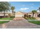 Inviting villa features a brick driveway, lush landscaping, and a two-car garage, creating a picturesque curb appeal at 7632 Quinto Dr, Sarasota, FL 34238