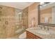 Modern bathroom featuring a tiled shower with glass door and granite vanity with bronze fixtures at 8779 Midnight Pass Rd # 506H, Sarasota, FL 34242