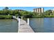 Wooden dock extending into the water, with a building visible through the green foliage in the background at 8779 Midnight Pass Rd # 506H, Sarasota, FL 34242