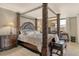 Elegant primary bedroom with four poster bed, sitting area, bedside tables and lamps at 8779 Midnight Pass Rd # 506H, Sarasota, FL 34242