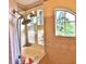 Bathroom with a bathtub and shower behind glass and unique tile work around the window at 950 Trotter St, Nokomis, FL 34275
