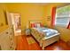 Bright bedroom with wooden floors, yellow walls, and a white bed frame with colorful floral bedspread at 950 Trotter St, Nokomis, FL 34275