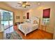 Brightly lit bedroom with wood flooring, ceiling fan, sliding doors to the pool, and windows with dark burgundy shades at 950 Trotter St, Nokomis, FL 34275