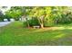 A beautifully landscaped front yard with a bench, mature trees, and lush green grass at 950 Trotter St, Nokomis, FL 34275