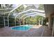 Screened-in pool area with a clear blue pool, surrounded by brick pavers and lush greenery at 950 Trotter St, Nokomis, FL 34275