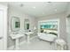 Elegant bathroom with clawfoot tub overlooking the pool and outdoor seating area at 102 77Th St, Holmes Beach, FL 34217