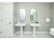 Bathroom with double vanity with sinks, decorative mirrors, and white tile flooring at 102 77Th St, Holmes Beach, FL 34217
