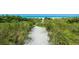 Sandy path leading to the beach, framed by tall grasses and lush greenery at 102 77Th St, Holmes Beach, FL 34217