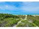 Scenic walk to beach through lush greenery, promising serene seaside escapes and relaxation at 102 77Th St, Holmes Beach, FL 34217