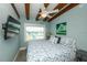 Cozy bedroom with wood-beamed ceiling, ceiling fan, flat screen TV, and beach view at 102 77Th St, Holmes Beach, FL 34217