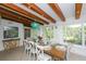 Dining room with wood beams, decorative chandelier, and a view of the green outdoors at 102 77Th St, Holmes Beach, FL 34217
