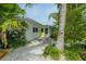 Charming home featuring a bright yellow door, white exterior, and tropical landscaping at 102 77Th St, Holmes Beach, FL 34217