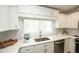 White kitchen features white cabinets, stainless steel sink, countertops, and modern appliances at 102 77Th St, Holmes Beach, FL 34217