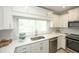 Bright kitchen features white cabinets, stainless steel sink, countertops, and stainless steel appliances at 102 77Th St, Holmes Beach, FL 34217